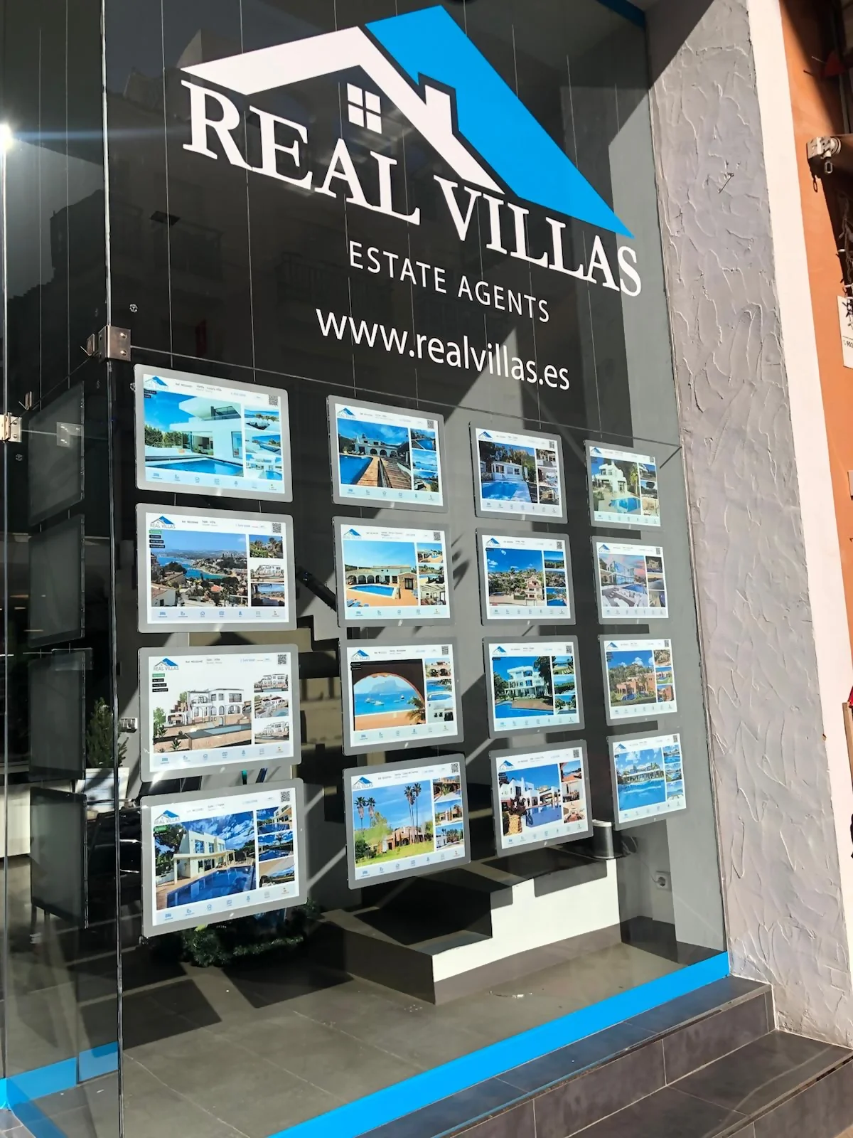 Escaparate de inmobiliaria en Alicante adaptado a compradores de segunda residencia con carpetas LED y viviendas de costa