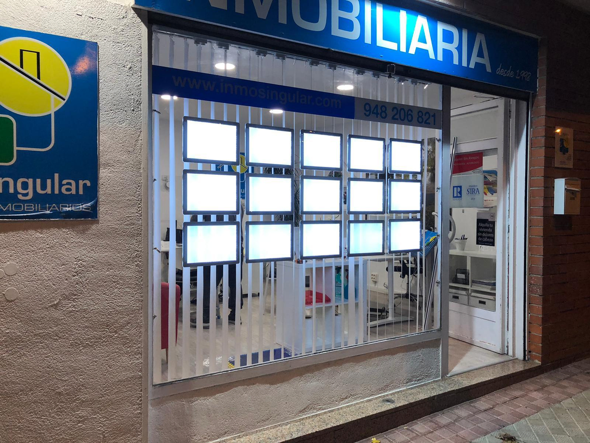 Escaparate inmobiliario en Valencia en una calle secundaria con carpetas LED visibles desde la acera