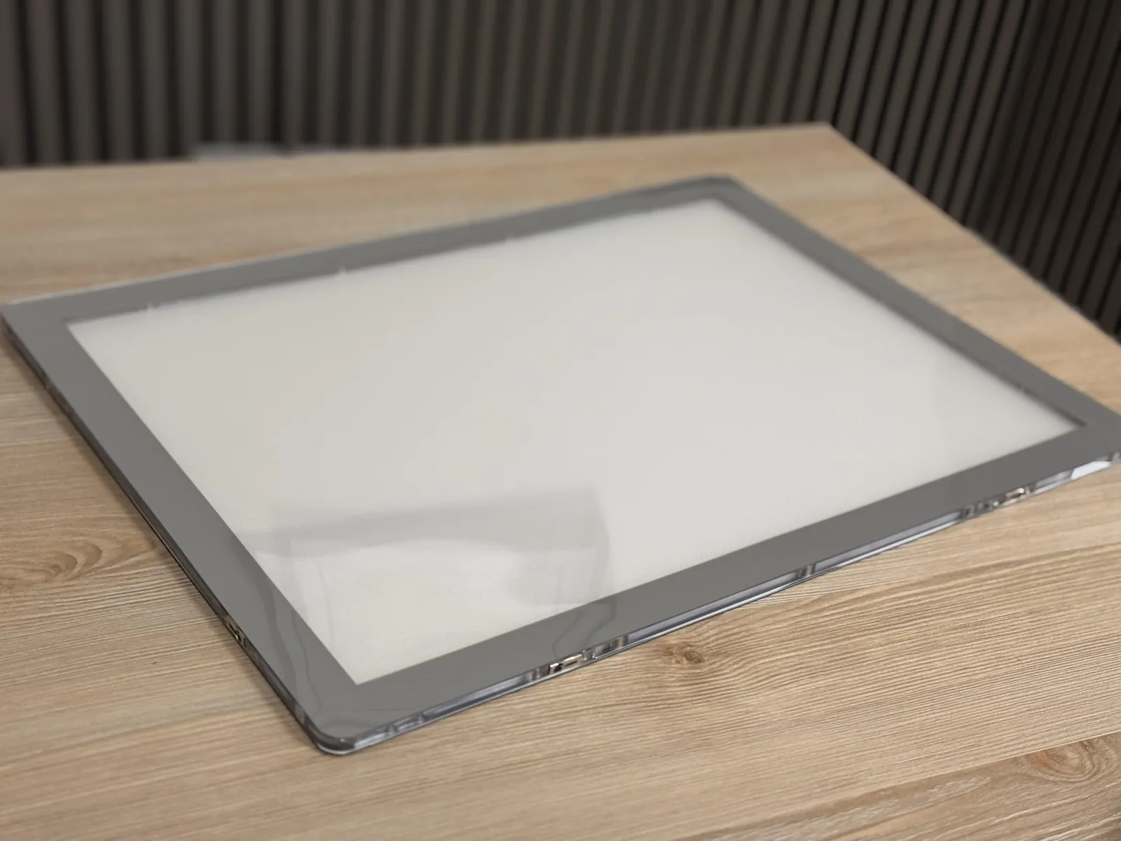 Carpeta LED A3 horizontal con marco gris y superficie translúcida retroiluminada sobre una mesa de madera